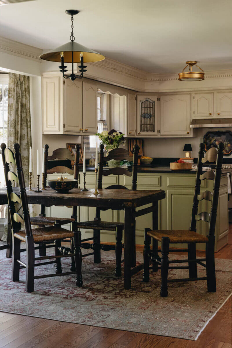 From ICU Nurse to Interior Designer: Meet Gretchen Rose of Kentucky Rose Designs - 14 A dining table with spindle-back chairs, designed by Gretchen Rose, sits in front of a kitchen with light-colored cabinets and a green island.