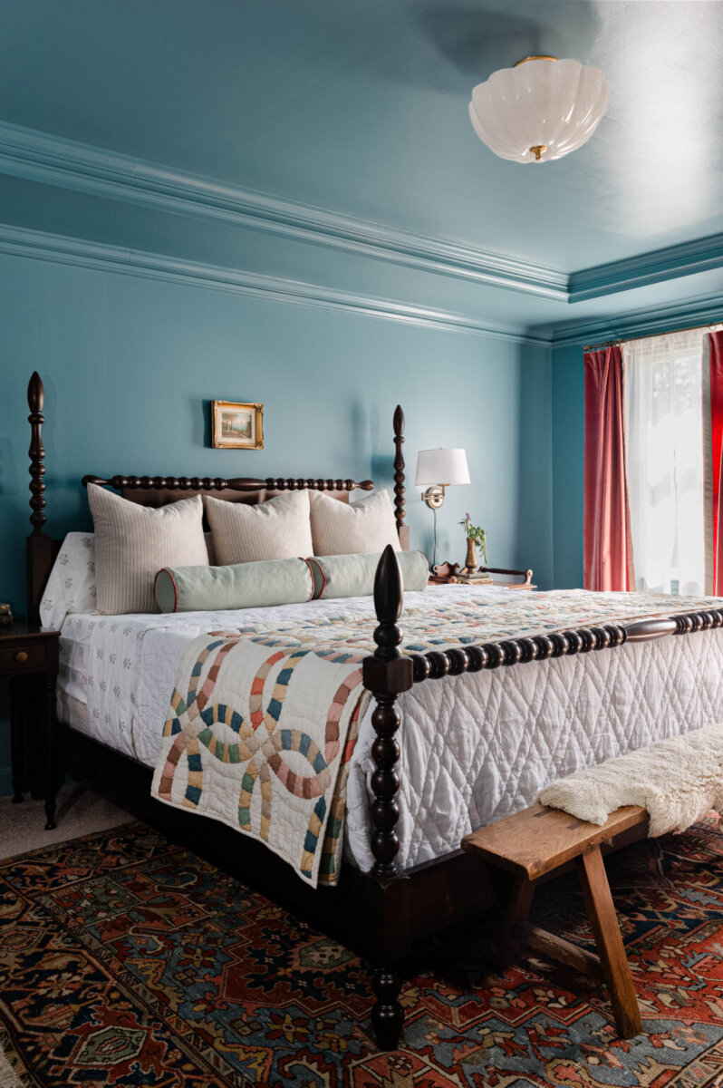 From ICU Nurse to Interior Designer: Meet Gretchen Rose of Kentucky Rose Designs - 16 A Gretchen Rose bedroom design featuring blue walls and ceiling, a dark wood four-poster bed with a patchwork quilt, and a patterned rug.