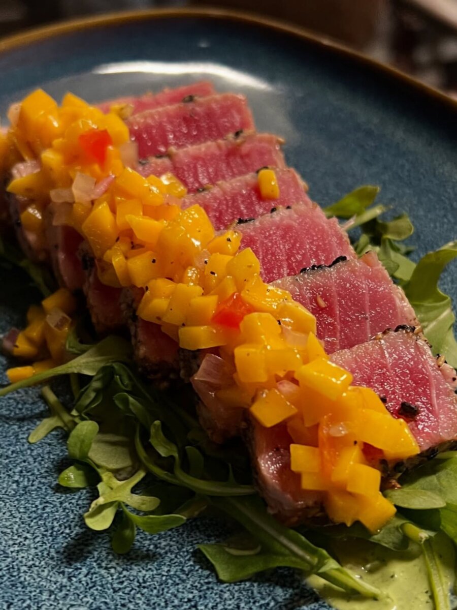 Sliced seared tuna topped with diced mango salsa on a bed of greens, a fresh highlight of Louisville dining.