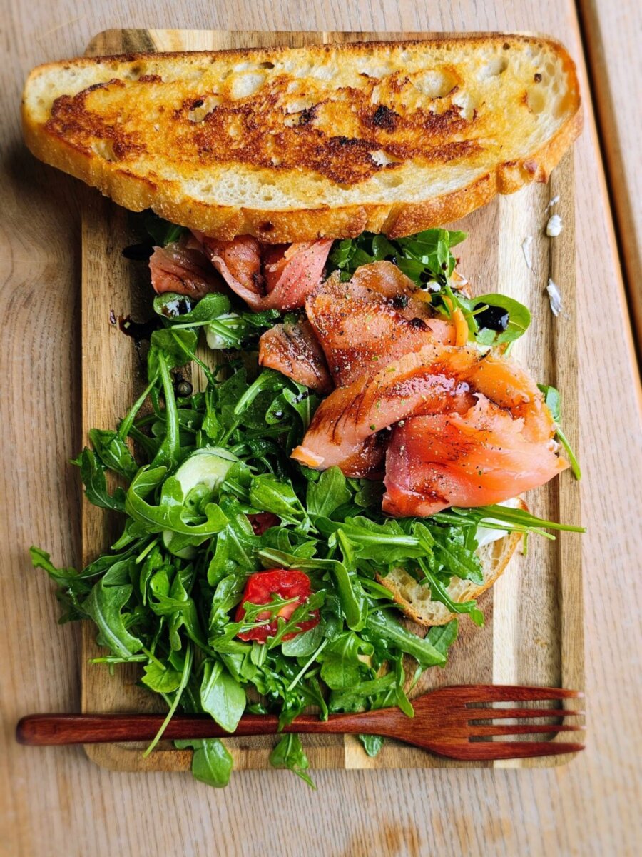 Smoked salmon and arugula salad on toasted bread on a wooden board, showcasing a highlight of Louisville dining.