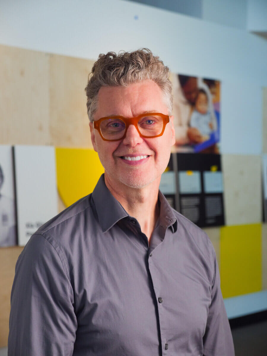 Stevie Wonder's Piano, Helen Keller's Desk & the Louisville Museum Where Every Guest Gets to Touch History - 4 A man with grey hair, orange-rimmed glasses, and a grey collared shirt at the Dot Experience immersive art installation.
