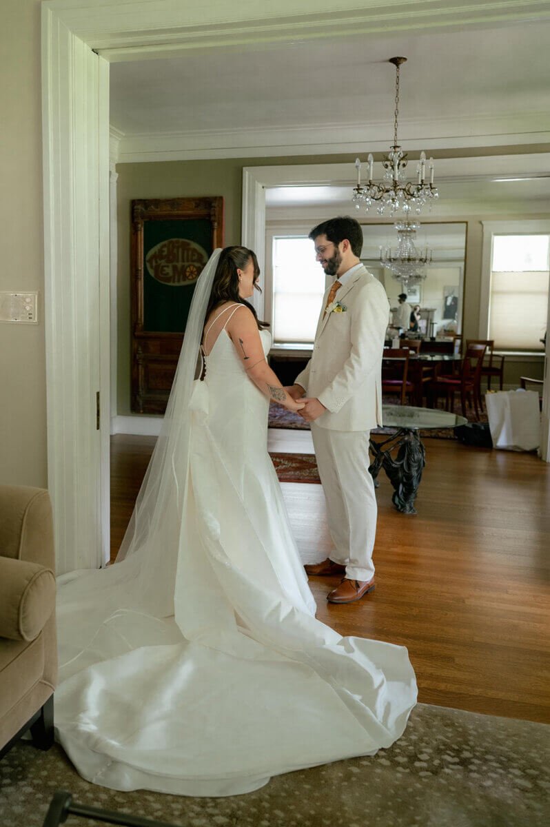 This Music-centric Memphis Wedding Even Had a Tattoo Artist! - 4 A bride in a white wedding gown and veil holds hands with a groom in a beige suit during their Memphis wedding celebration.