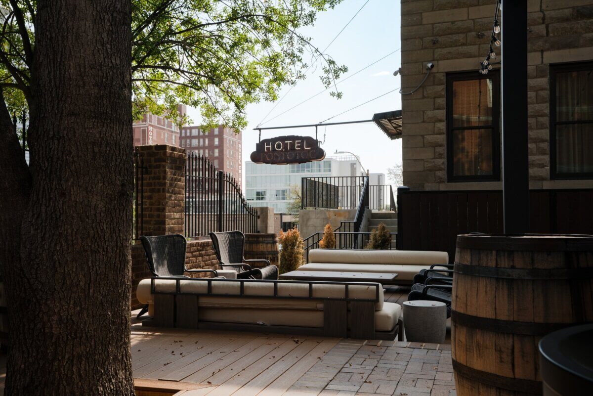 You Won't Believe What They Found Inside This 120-Year-Old Memphis Hotel - 7 Outdoor patio lounge furniture beneath a hanging Hotel Pontotoc sign, showcasing historic hotel design.