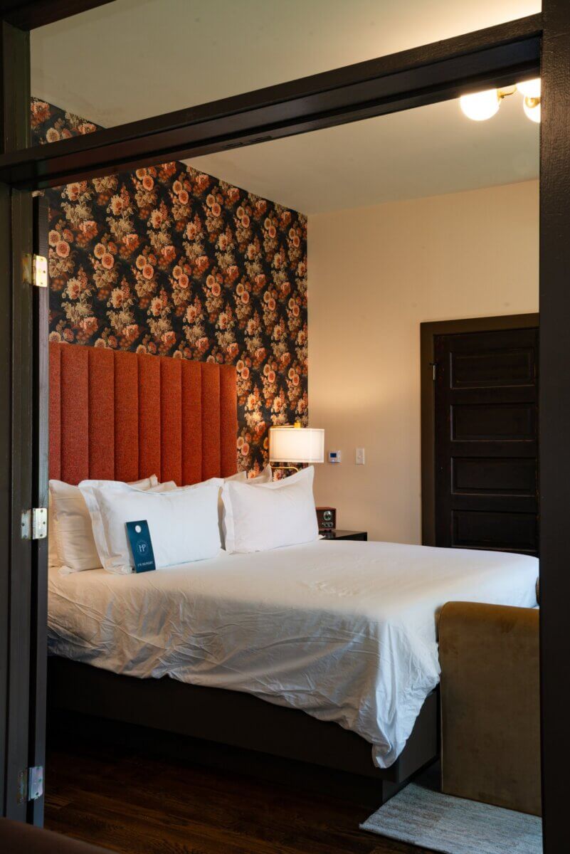 You Won't Believe What They Found Inside This 120-Year-Old Memphis Hotel - 11 Hotel room with a tall orange headboard against a floral wallpaper accent wall, showcasing the boutique hotel design of Hotel Pontotoc.