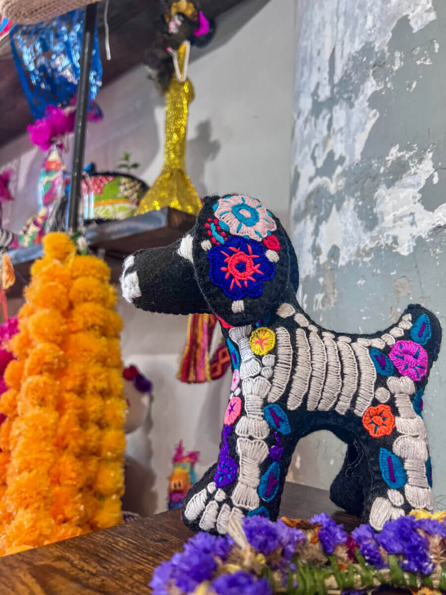 A Memphis Día de los Muertos Guide: Where to Celebrate - 2 A black dog figurine with skeleton embroidery and floral patterns.