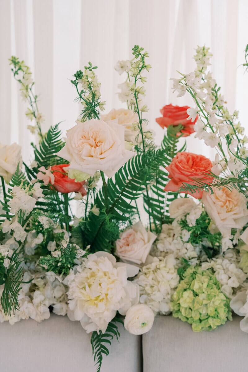 A Secret Speakeasy and Late-Night Taco Bell?! This Nashville Wedding Had Serious Surprises - 6 A garden party wedding floral arrangement with white and coral roses, white delphinium, hydrangeas, and green ferns.