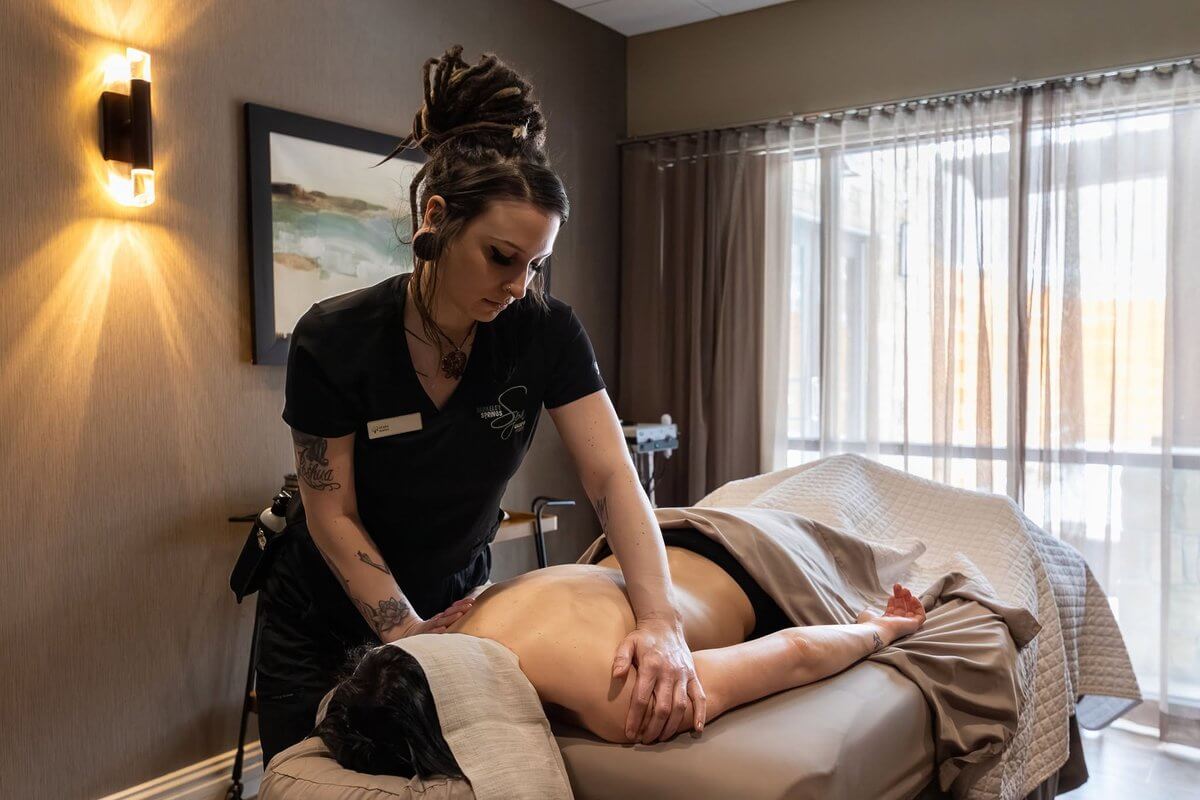 A massage therapist works on a client lying on a treatment table at a park lodge.