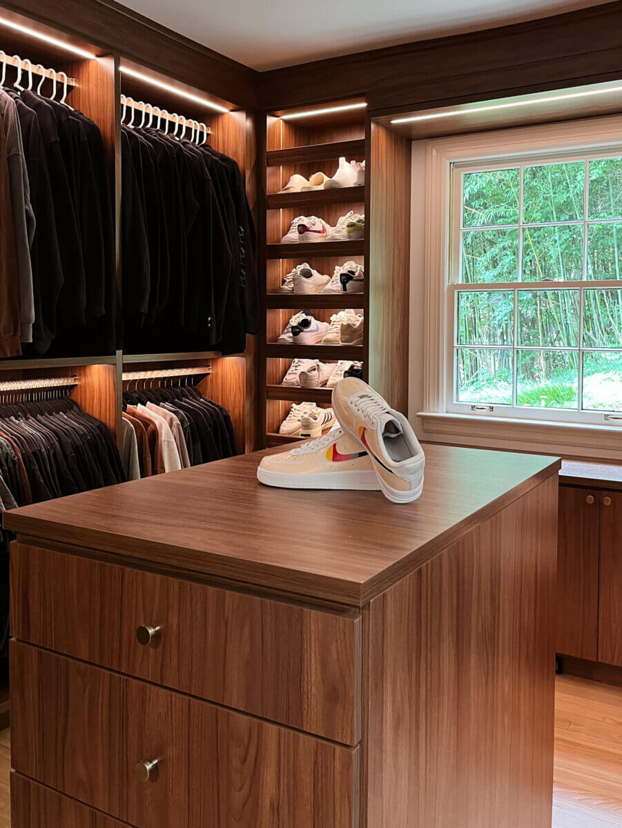 Want to Increase Your Home's Resale Value? Consider a Custom Closet - 4 A custom closet with wooden shelves and racks organizing clothes and shoes; a pair of white sneakers with an orange swoosh sits on the center island to increase resale value.