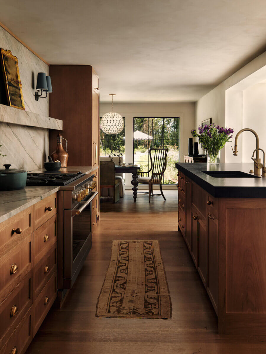 They Abandoned Their Dream Home Plans. Here's What Happened Next. - 8 Kitchen with wooden cabinets, marble countertops, a central island, and a dining area visible through an open doorway.