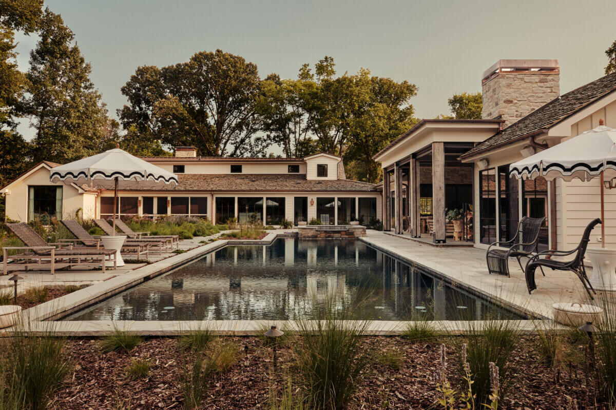 They Abandoned Their Dream Home Plans. Here's What Happened Next. - 2 Rectangular swimming pool bordered by a stone patio, lounge chairs, and umbrellas in front of a modern house.
