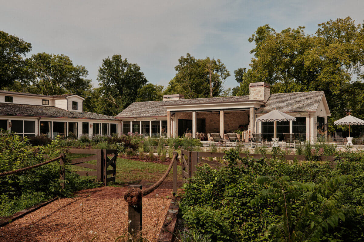 They Abandoned Their Dream Home Plans. Here's What Happened Next. - 4 A farmhouse-style home with a covered patio, surrounded by gardens and a gravel path with a rope fence.