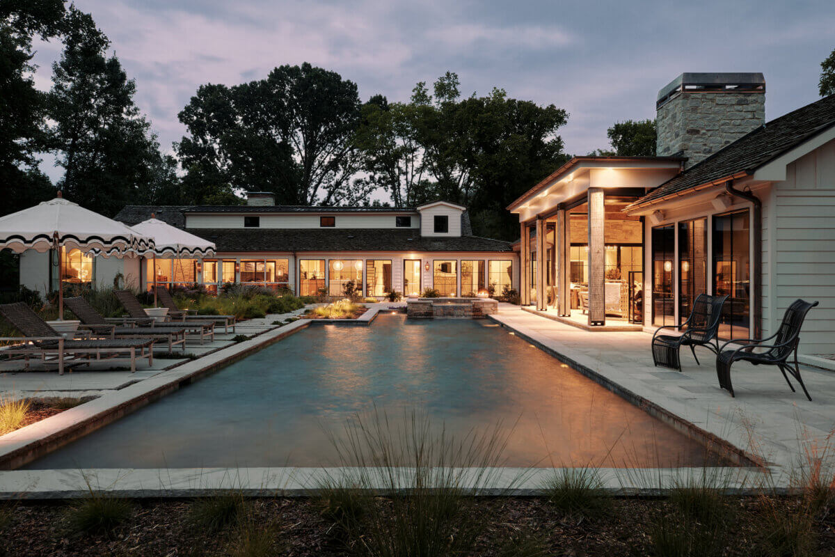 They Abandoned Their Dream Home Plans. Here's What Happened Next. - 16 Modern single-story house with a rectangular swimming pool, patio seating, and poolside umbrellas at dusk.