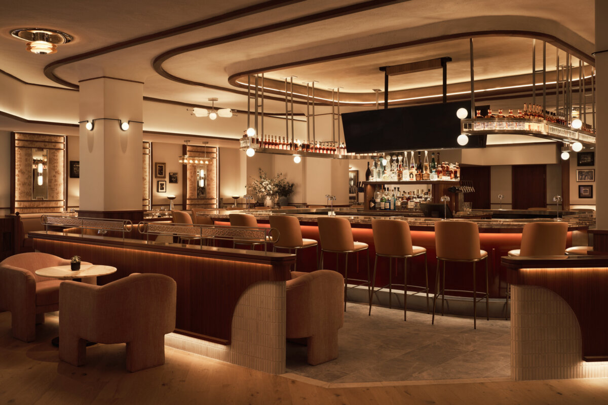 Nashville Steals, Deals & Announcements: October 2026 - 12 Modern bar interior with curved counter, upholstered stools, ambient lighting, and stocked shelves. Enjoy warm, neutral tones and discover exclusive October deals in this inviting space.