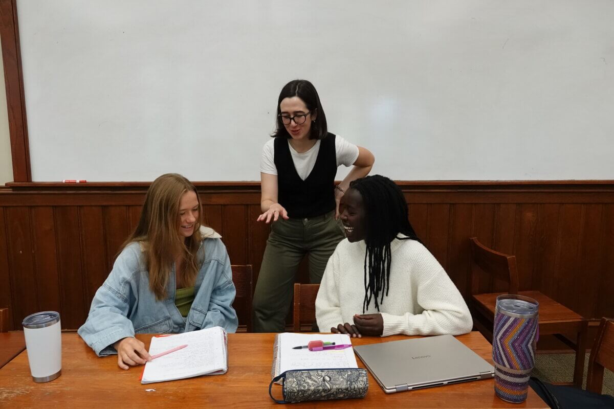 5 Reasons This Idyllic TN Private School Might Be Right for Your Family - 3 Three college prep high school students laughing and talking while sitting at a table in a classroom with a whiteboard.
