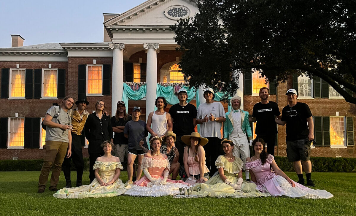 The Haunted Folklore of Mississippi Influenced This Costume Designer's Career - 6 A group of fifteen people in a mix of modern casual wear and 19th-century attire designed by a costume designer pose on the lawn in front of a haunted house.