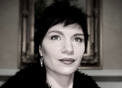 Portrait of a costume designer with short dark hair looking upward.