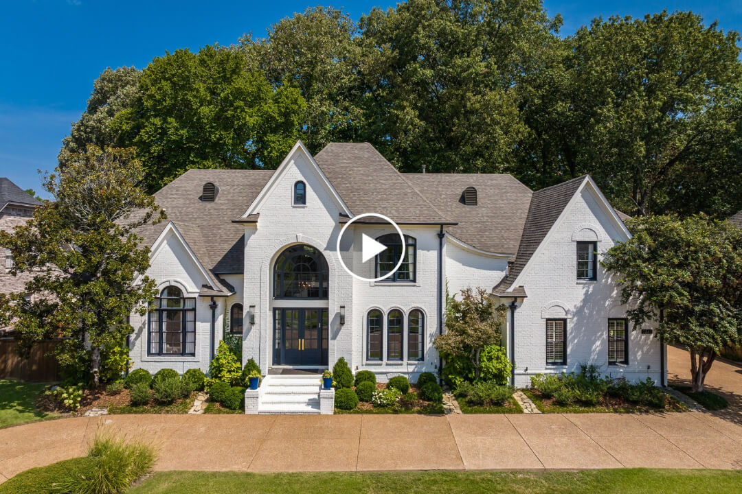 Two-story white brick house at 7562 Tagg Dr with a steep roof, arched windows, and a paved driveway, representing quality Germantown TN real estate.