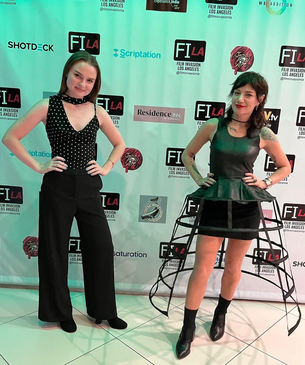 The Haunted Folklore of Mississippi Influenced This Costume Designer's Career - 4 A costume designer and a writer-director pose on a step-and-repeat backdrop at Film Invasion Los Angeles.