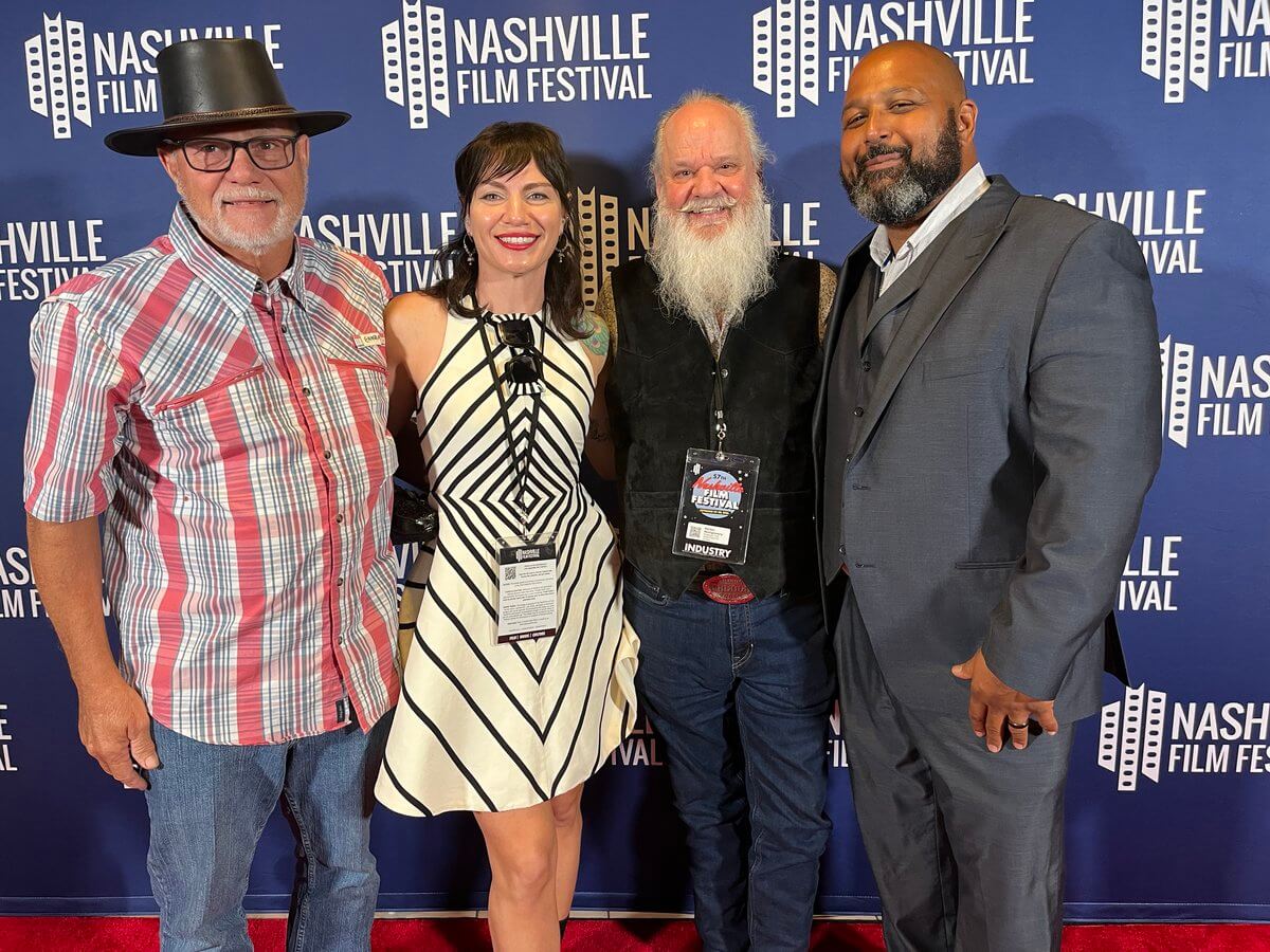 The Haunted Folklore of Mississippi Influenced This Costume Designer's Career - 7 Four people, including a writer-director and a costume designer, pose for a photo in front of a blue Nashville Film Festival step-and-repeat backdrop.
