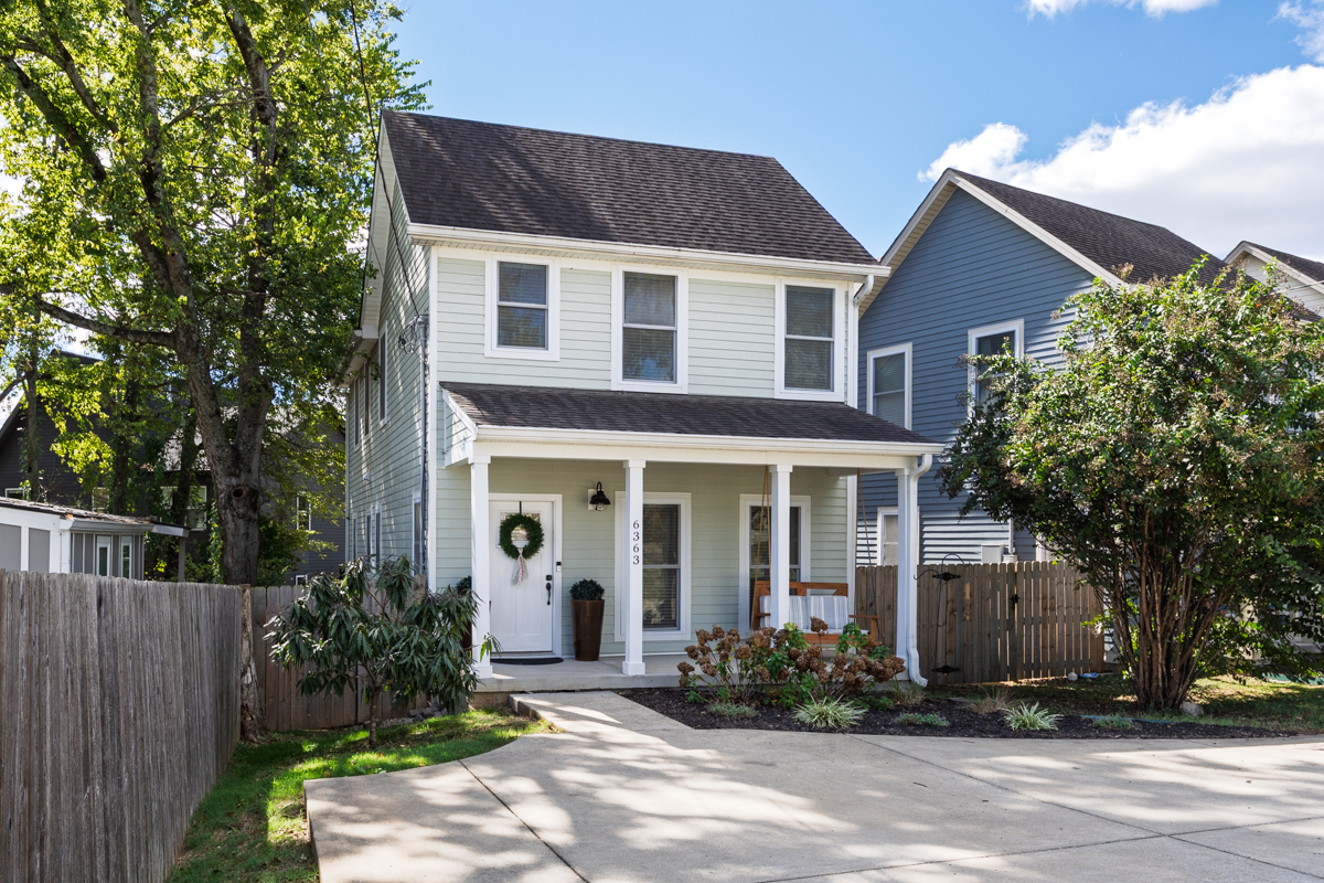 Two-story light green Nashville property with a front porch, a wreath on the door, and the address 6363 on the column.