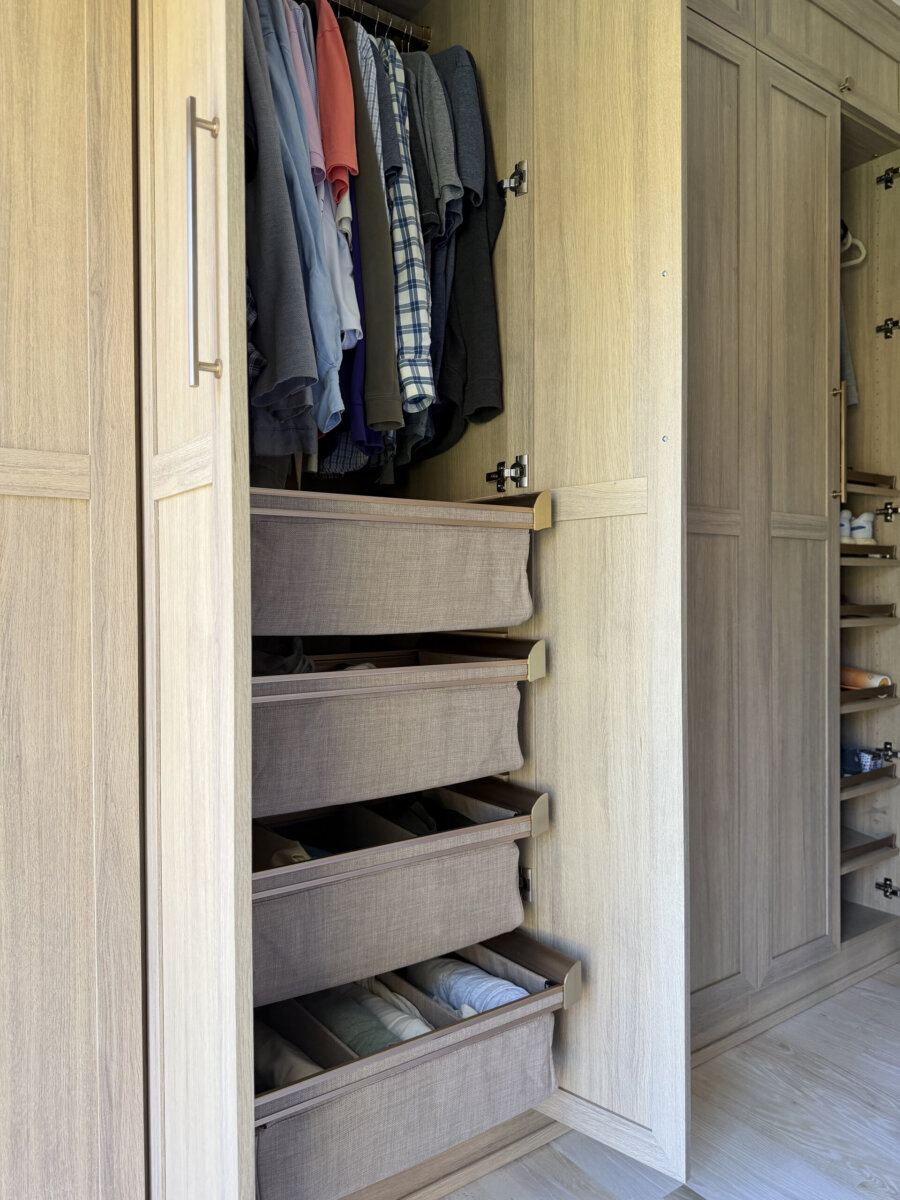 Open wooden wardrobe with hanging winter clothes on the top rack and four pull-out fabric drawers below for easy closet organization.